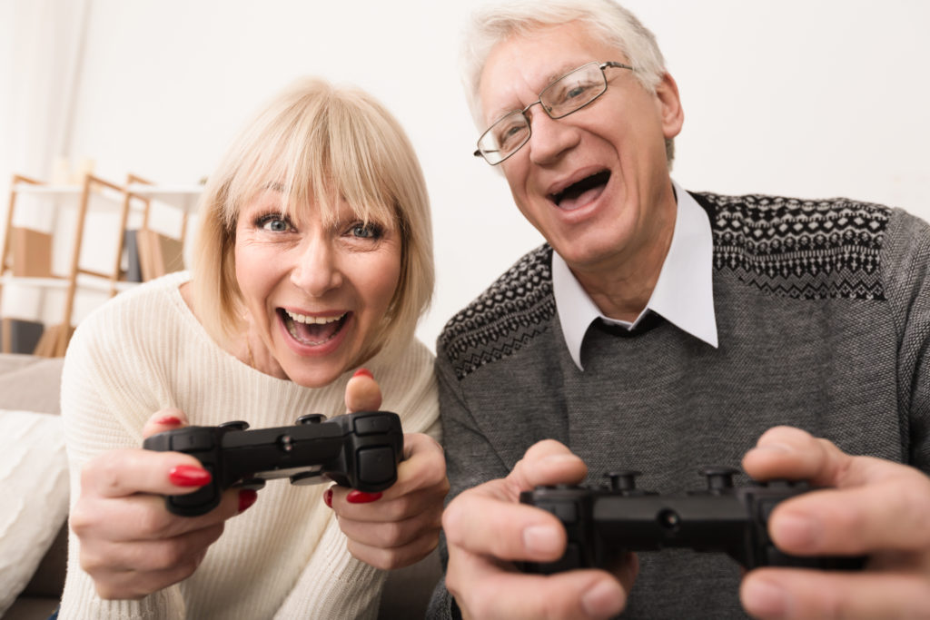 Senior couple playing video games together at home